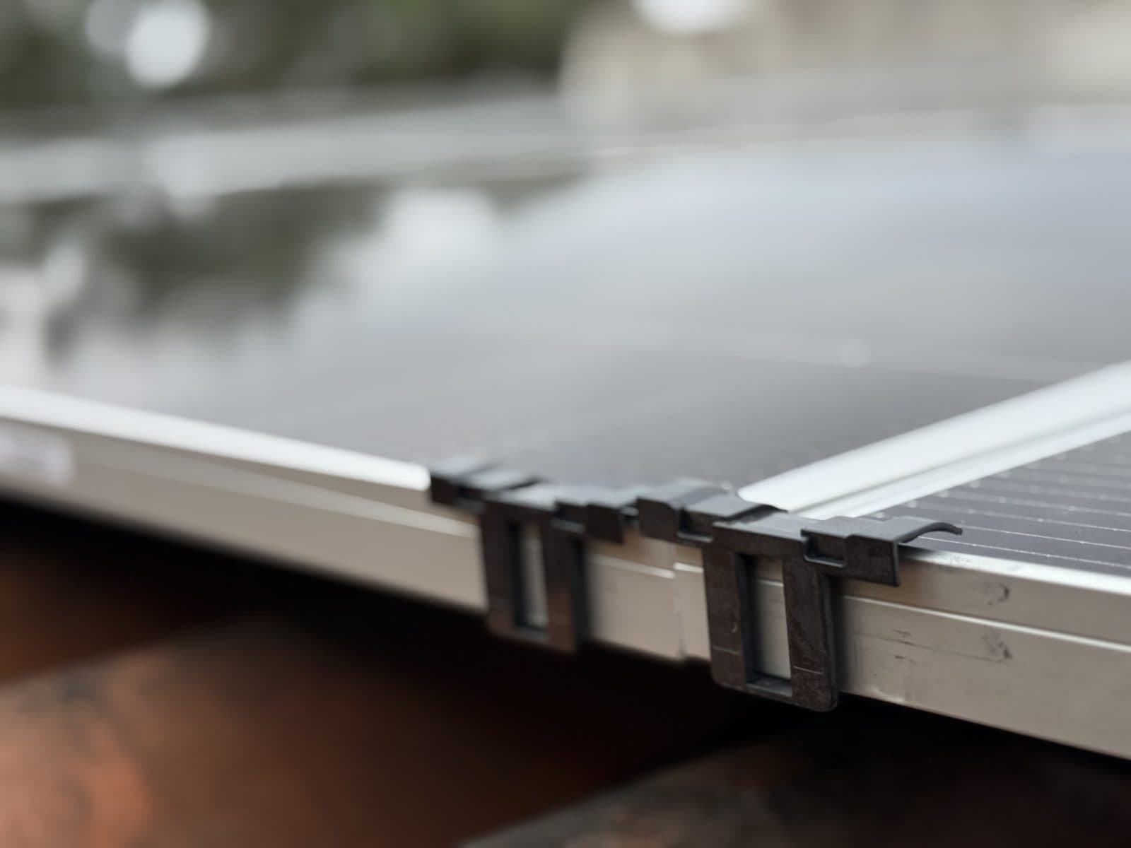 Primer plano de las grapas metálicas que sujetan dos placas por su marco de aluminio
