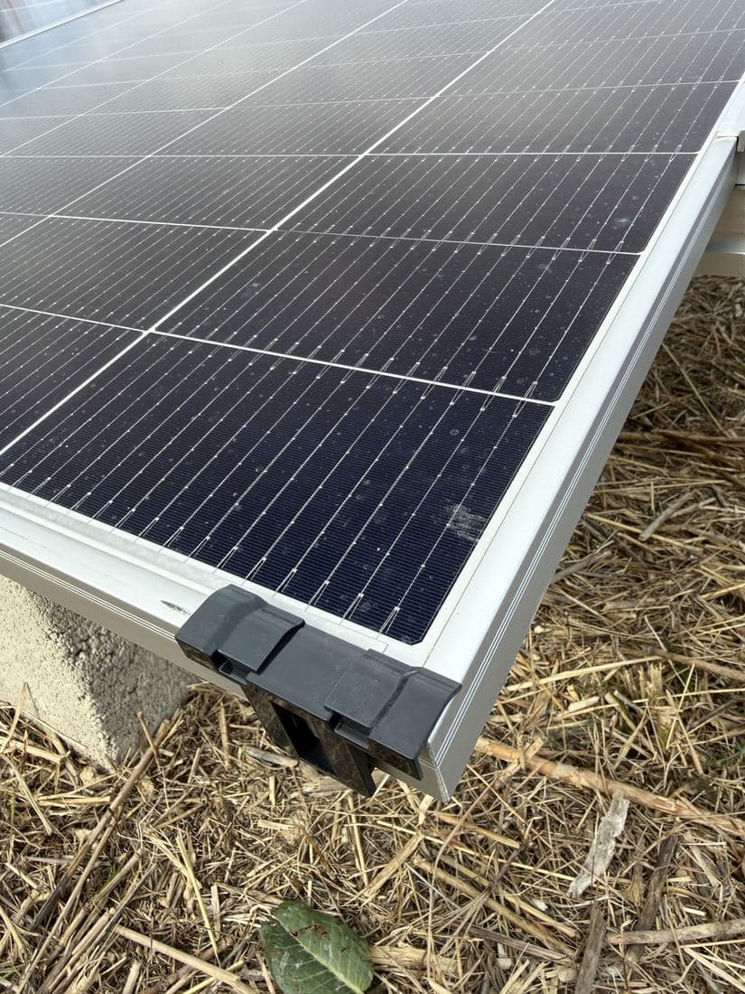 Primer plano de la esquina de una placa y su grapa, en una instalación sobre suelo